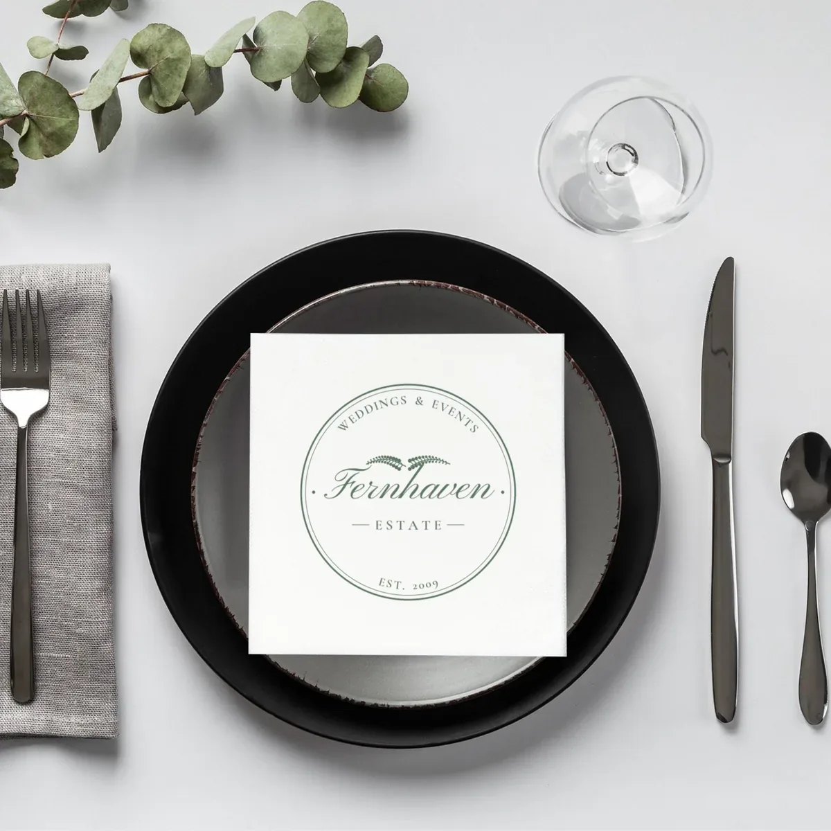 Cocktail napkin on a place setting printed with a sample venue logo